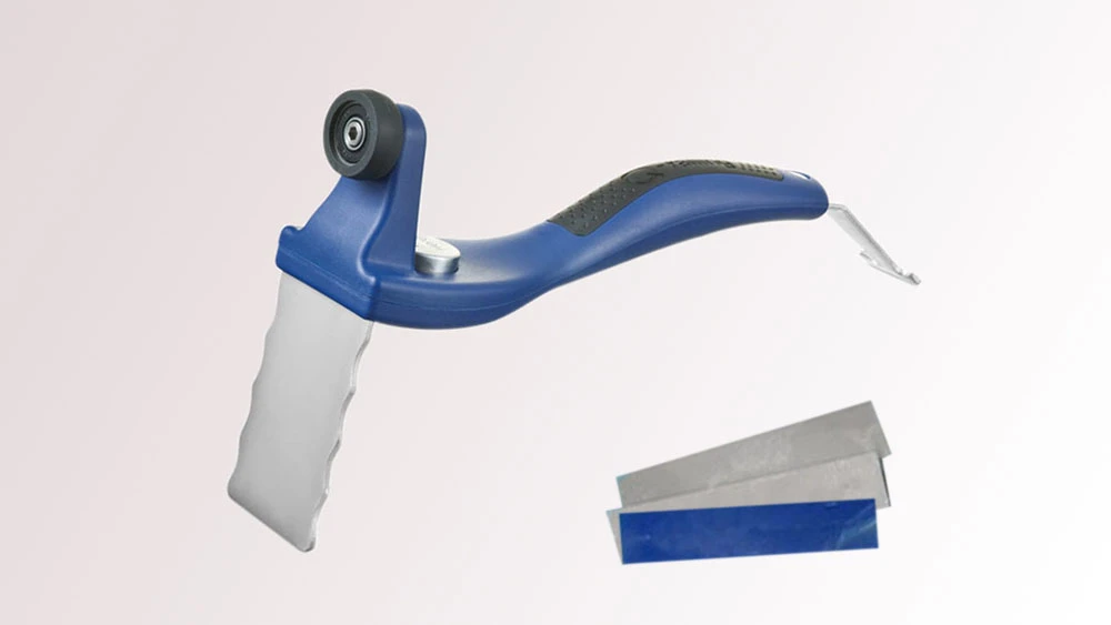 Handentgrater mit blauem Griff, Metallklinge und kleiner Rolle, daneben zwei Ersatzklingen mit blauer Aufnahme